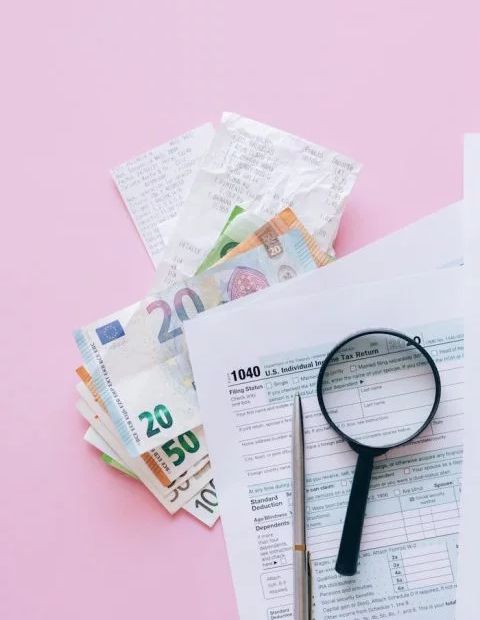 Stos banknotów i lupa na stole, symbolizujące analizę finansową.